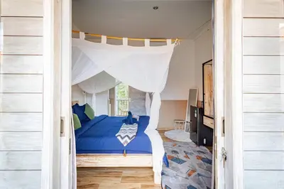 a bedroom with a blue bed with a canopy at Kubu Guest House in Seminyak
