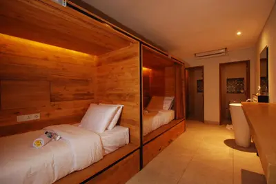 a bedroom with two beds with wooden walls at DBeds Kuta Beach in Kuta