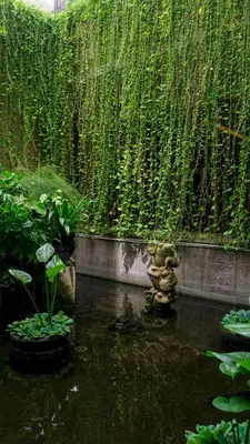 a teddy bear statue in a pond in a garden at Tusita Boutique Hotel in Kuta