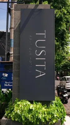 a sign for a hotel on the side of a street at Tusita Boutique Hotel in Kuta