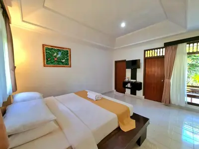 a hotel room with a bed and a television at Satriya Cottages in Kuta