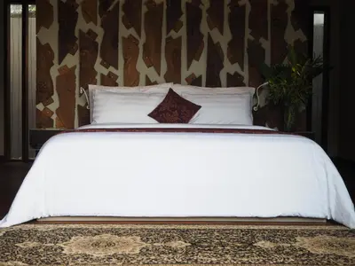 a bed with white sheets and pillows on it at Pronoia Beach Resort in Jimbaran