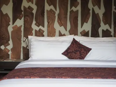 a bed with white pillows and a wooden headboard at Pronoia Beach Resort in Jimbaran