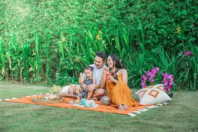 a man and woman sitting on a blanket with a baby at Samaja Beachside Villas in Seminyak