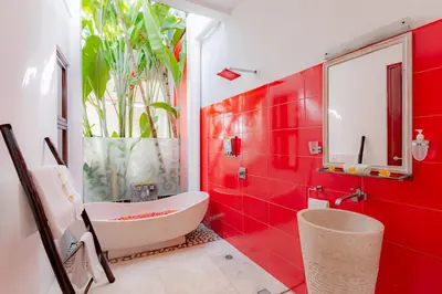 a red bathroom with a white tub and red tiles at Bali Ginger Suites & Villa in Seminyak