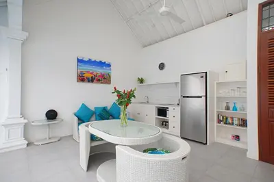 a white kitchen with a table and a refrigerator at Villa Ley Double Six by Best Deals Asia Hospitality in Seminyak