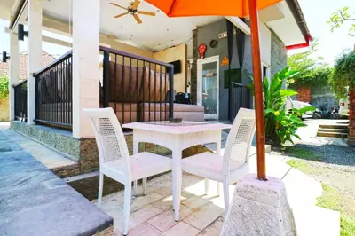 a table and chairs with an umbrella on a patio at Lembayung Sari Homestay in Denpasar