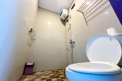 a bathroom with a toilet with the lid up at Lembayung Sari Homestay in Denpasar