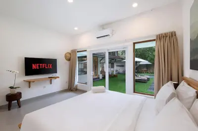 a bedroom with a white bed and a tv at Best Location 7 Bed, 7,5 Bath Pool Villa, near beach in Kuta