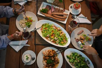 a group of people sitting around a table with plates of food at Best Location 7 Bed, 7,5 Bath Pool Villa, near beach in Kuta