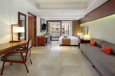 a hotel room with a bed and a couch and a desk at The Magani Hotel and Spa in Legian