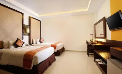 a hotel room with two beds and a desk at Best Western Kuta Villa in Kuta