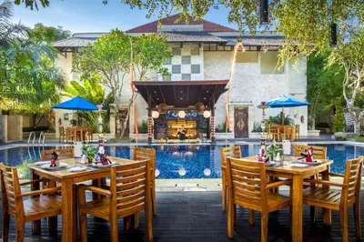 a restaurant with tables and chairs next to a pool at Best Western Kuta Villa in Kuta