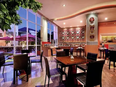 a restaurant with tables and chairs and large windows at Ibis Bali Kuta in Kuta