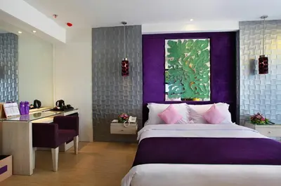 a bedroom with a bed and a desk and a window at Grand Mega Resort & Spa Bali in Kuta