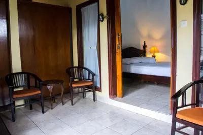 a room with a bed and a table and chairs at Putu Guest House in Canggu
