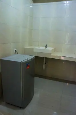 a bathroom with a sink and a small refrigerator at Putu Guest House in Canggu