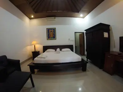 a bedroom with a bed and a chair and a couch at Putu Guest House in Canggu