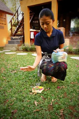 a woman sitting on the grass in the yard at Petit Tree in Seminyak