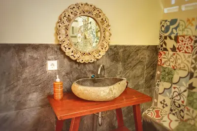 a bathroom with a stone sink and a mirror at Petit Tree in Seminyak