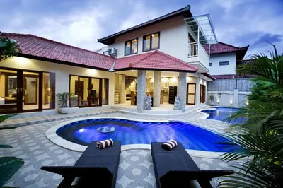 a house with a swimming pool in front of a house at Villa Chambertin in Seminyak