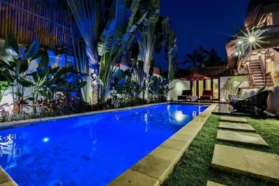 a swimming pool in the yard of a house at night at Villa Champagne in Seminyak