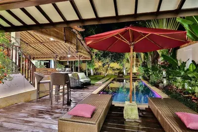 a pool with a red umbrella and a table and chairs at Villa Champagne in Seminyak