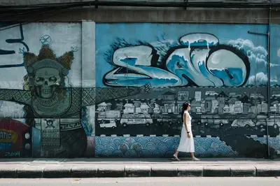a woman walking on a sidewalk in front of a mural at Lloyd's Inn Bali in Seminyak