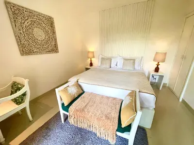 a bedroom with a large bed and a chair at La Belle Villa in Seminyak