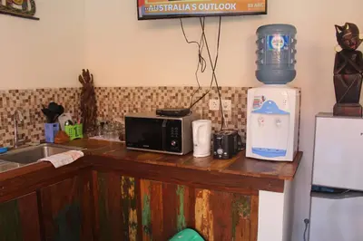 a kitchen counter with a microwave and a bottle of water at Jukung Villas Kuta in Kuta