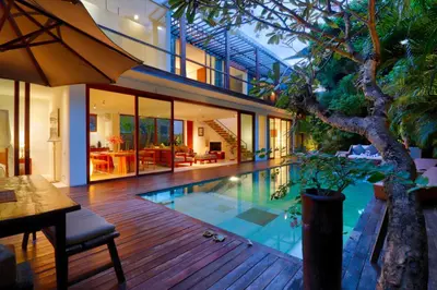 an indoor swimming pool in a house with a tree at Beach Axis Villa, Seminyak in Seminyak