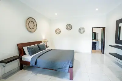 a bedroom with a bed in a white room at The Catur Villa Seminyak in Seminyak