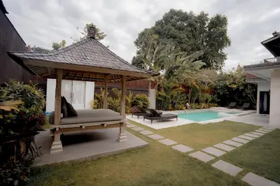 a gazebo with a bed next to a pool at The Catur Villa Seminyak in Seminyak
