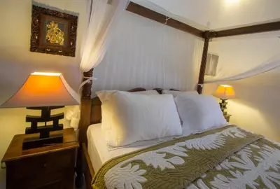 a bedroom with a bed and a lamp on a night stand at Villa Kamboja Senior in Legian