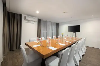 a conference room with a long wooden table and white chairs at The Akmani Legian in Legian