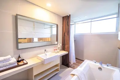 a bathroom with a sink and a mirror and a tub at The Akmani Legian in Legian