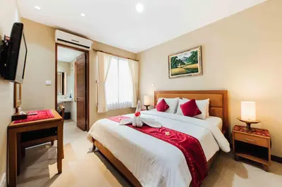 a bedroom with a large bed and a television at Kuta Puri Bungalows, Villas and Resort in Kuta