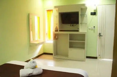 a room with a bed and a kitchen with a television at Dedy Beach Inn in Kuta