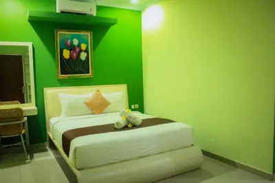 a green bedroom with a bed with a teddy bear on it at Dedy Beach Inn in Kuta