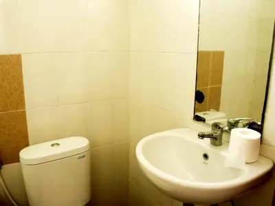 a bathroom with a toilet and a sink and a mirror at Agus Beach Inn in Kuta