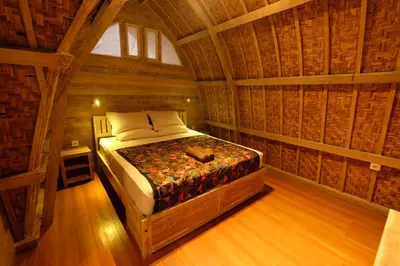 a bedroom with a bed in a log cabin at Villa Made West in Seminyak