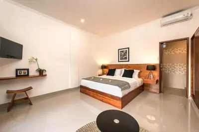 a bedroom with a bed and a tv on the wall at Puri Uma Ratu by RPM in Seminyak