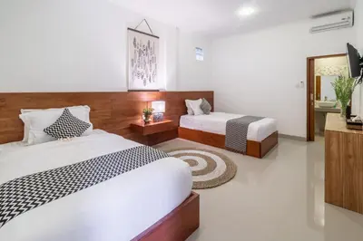 a hotel room with two beds and a mirror at Puri Uma Ratu by RPM in Seminyak