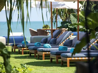 a row of chaise lounges with the ocean in the background at Noku Beach House by Elite Havens in Seminyak