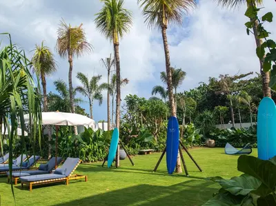 a group of chairs and palm trees in a yard at Noku Beach House by Elite Havens in Seminyak