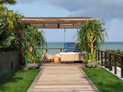 a wooden walkway leading to a patio with a couch at Noku Beach House by Elite Havens in Seminyak