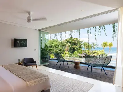 a bedroom with a bed and a balcony with the ocean at Noku Beach House by Elite Havens in Seminyak