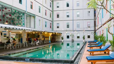 a pool in a building with chairs and tables at POP! Hotel Kuta Beach in Kuta