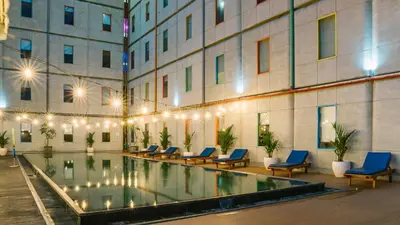 a hotel pool with blue chairs and a building at POP! Hotel Kuta Beach in Kuta