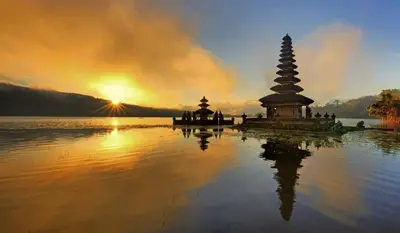 a temple in the water with the sunset in the background at POP! Hotel Kuta Beach in Kuta